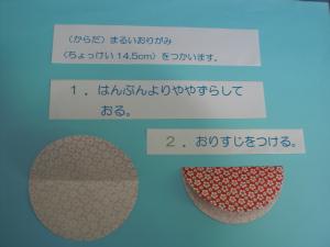 体をつくります。丸い折り紙(直径14.5㎝～15cm)を使います。半分より少しずらして折ります。
