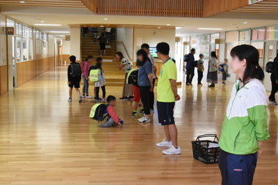 先生方が玄関前に並んで子供たちを出迎える風景