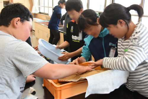 砂で川の地形を作る子供たち