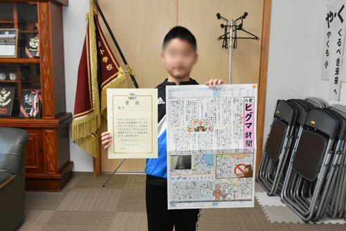 入賞した新聞と賞状を手にポーズ